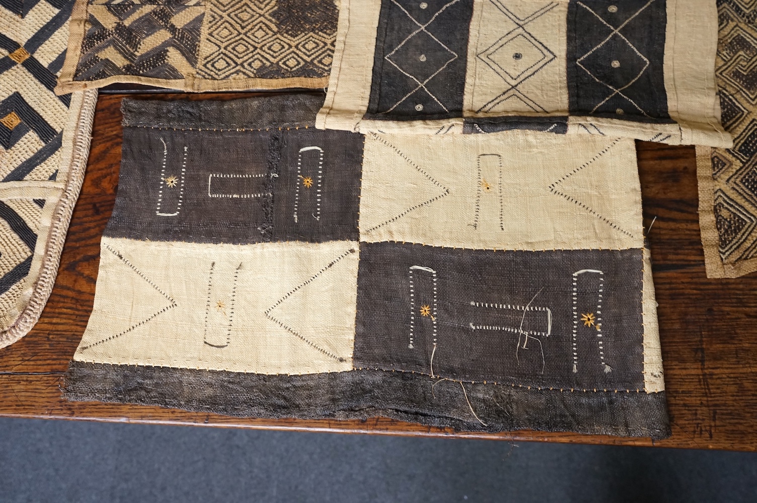 A collection of five 20th century African Congo hand woven and embroidered raffia palm leaf runners and mats, together with a later large printed hanging. 260cm x 138cm. Condition - one smaller mat has a hole in the weav